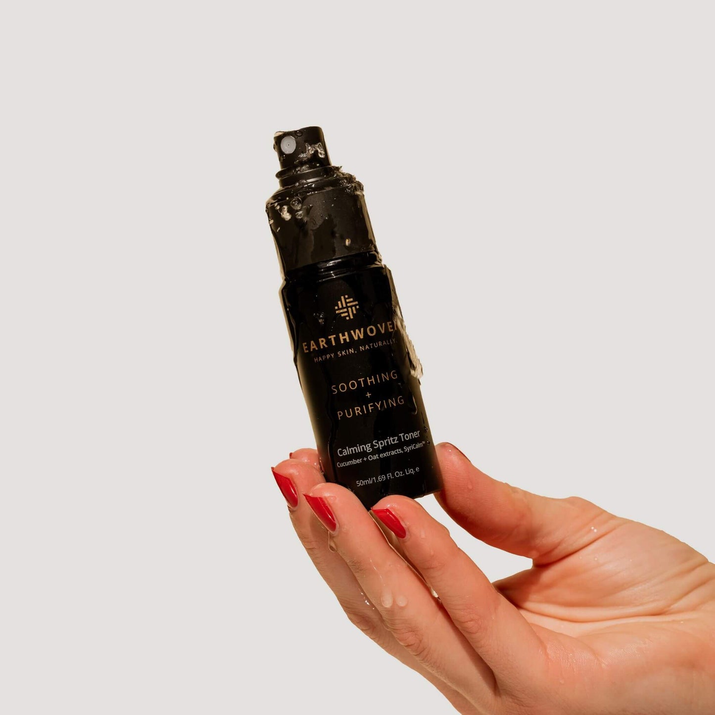 Calming Spritz Toner being held under water, highlighting its hydrating benefits for sensitive skin.
